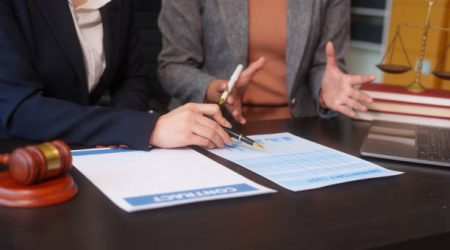 Close-up of two female lawyers hands working at desk, handling legal documents, drafting contracts and preparing for business meetings, specializing in legal and corporate legal services
